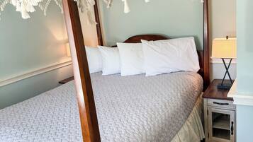 A four-poster bed with a white canopy, a wooden headboard, and a bedside table with a lamp.