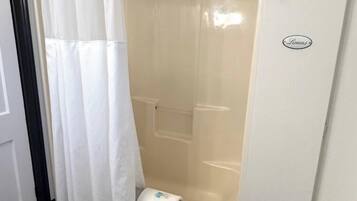 Un área de ducha con una cortina blanca, una toalla y una bañera.