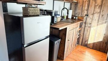 A compact kitchen with a refrigerator, microwave, and wooden cabinets.