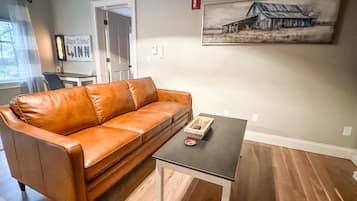 Una sala de estar con un sofá de cuero, una mesa de centro y un cuadro en la pared.