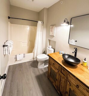 Bathroom features a vanity with a sink, large mirror, and shower area with a curtain.