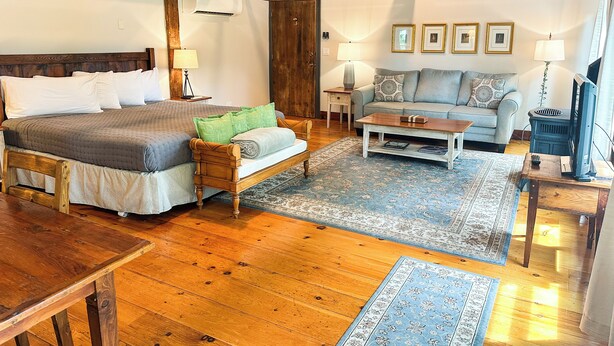 A room with a bed, a sofa, a coffee table, and a television. - Black Walnut Inn (Amherst)