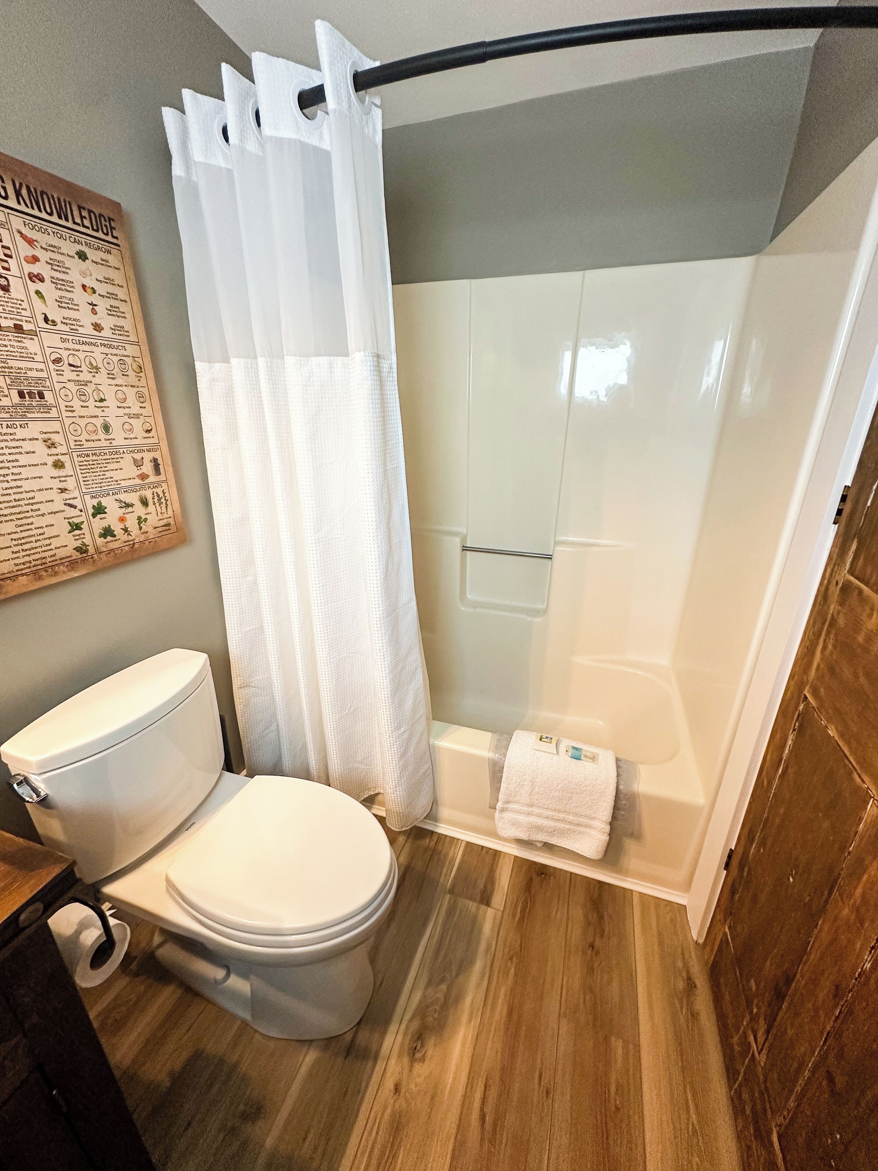 A bathroom with a toilet, shower, and a wall-mounted information board.