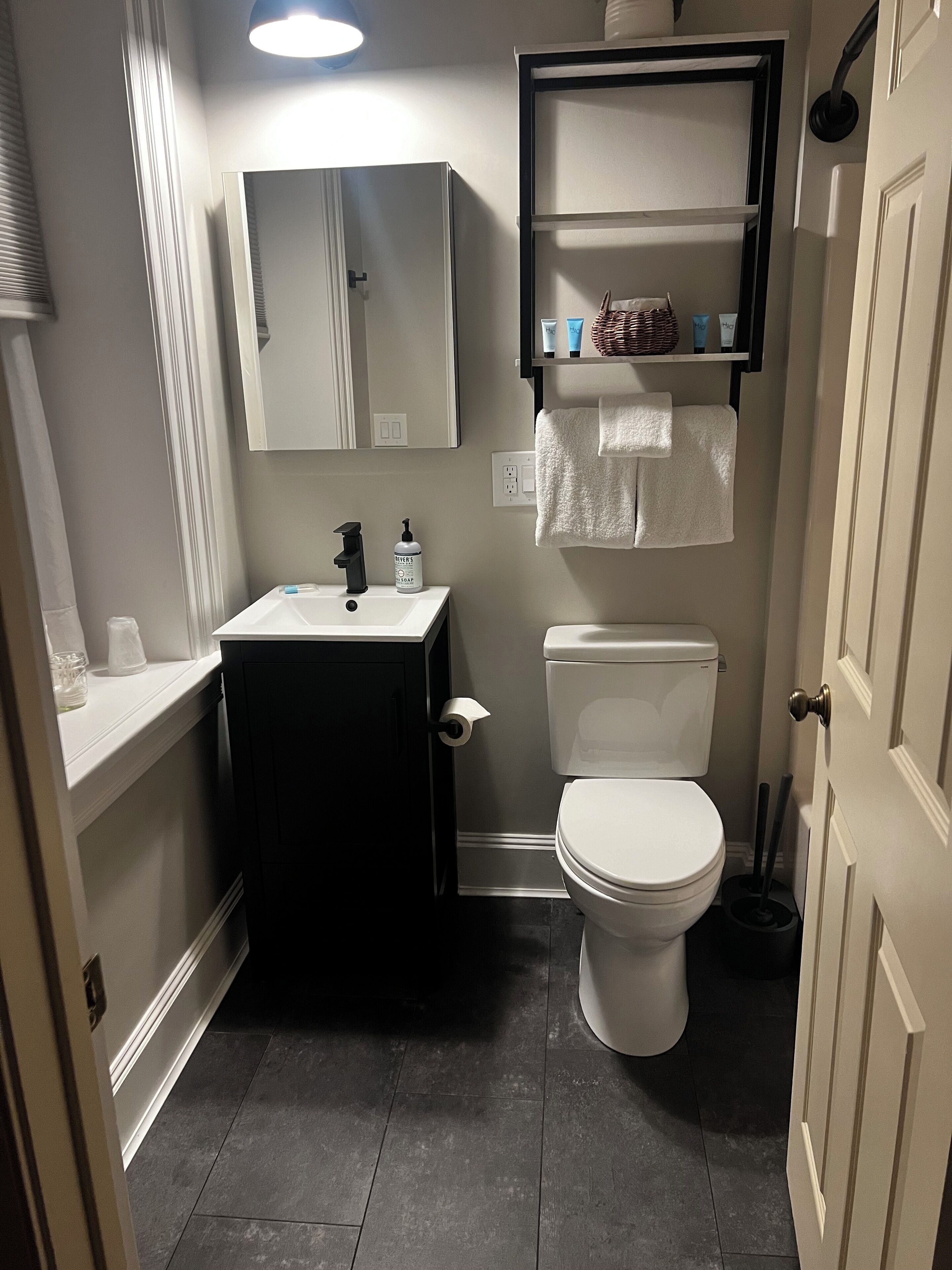 A compact bathroom with a white sink, a toilet, and a mirror above the sink.