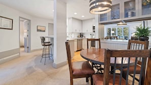 A modern kitchen with white cabinets, a central island, and a hanging light fixture. - The Charter at Beaver Creek D1205 (Beaver Creek)