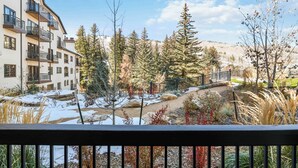 A multi-story building with balconies, a snow-covered landscape, and a variety of trees. - The Charter at Beaver Creek D1205 (Beaver Creek)