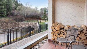 A balcony with a stone wall, a metal railing, and a stack of firewood. - The Charter at Beaver Creek D2705 (Beaver Creek)