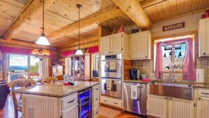 A kitchen with wooden cabinets, stainless steel appliances, and a central island with a built-in oven. - 24-0089 Rustic Hartsel Getaway w/ 35-Acre Yard (Fairplay)
