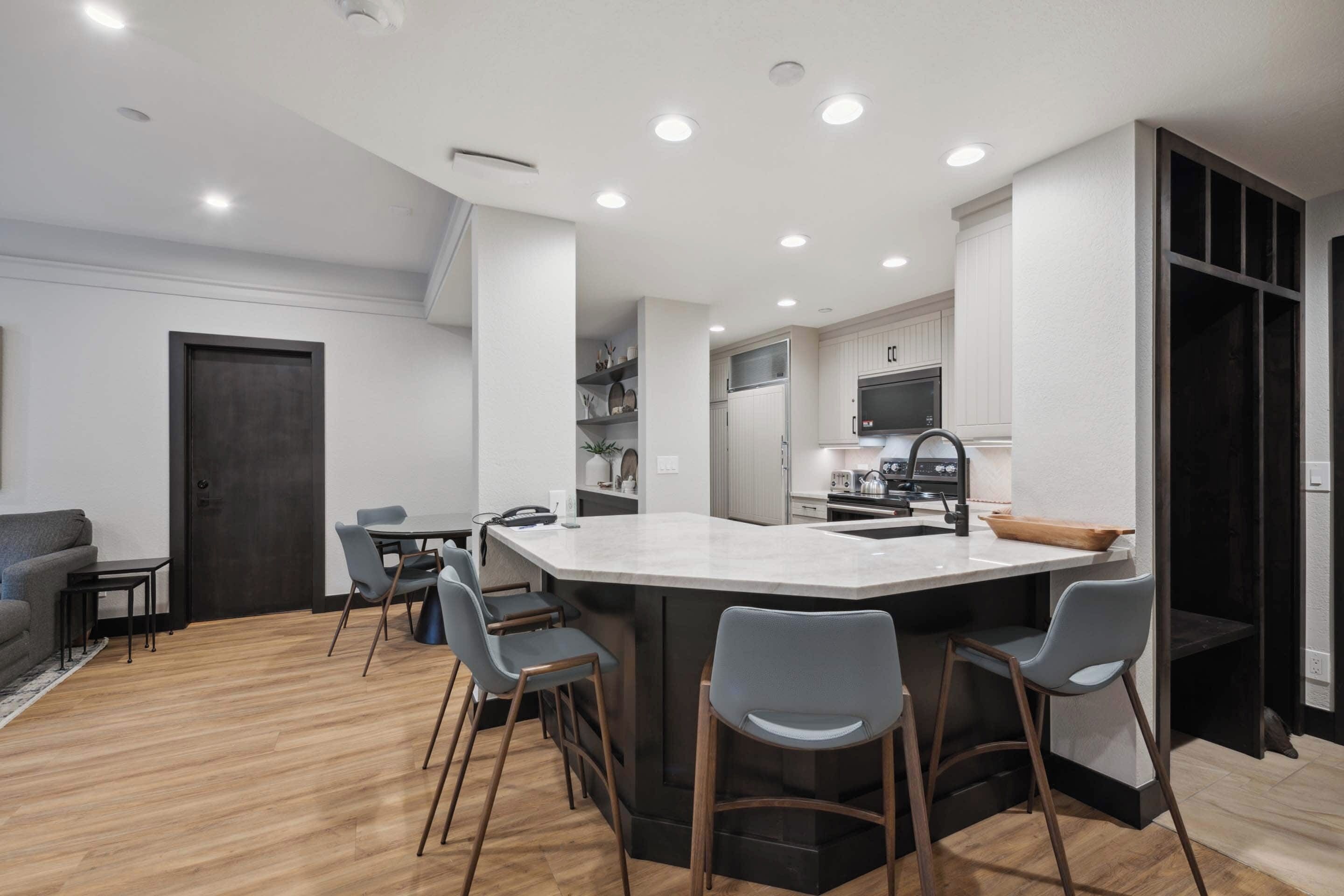 A modern kitchen with a central island, bar stools, and built-in appliances.