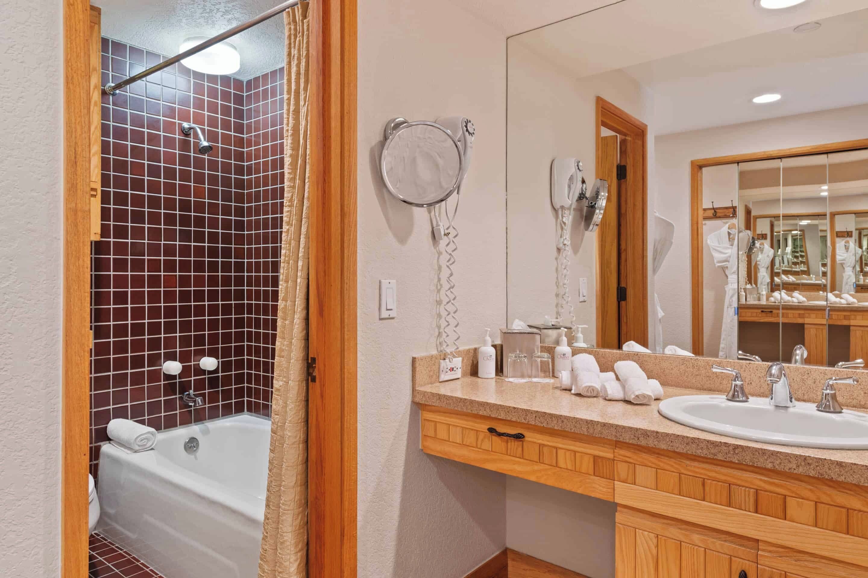 Een badkamer met een bad, wastafel, spiegel en een aan de muur bevestigde haardroger.