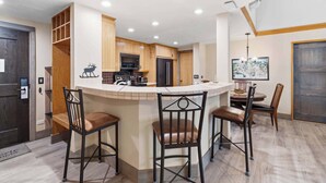 Une cuisine moderne dotée d’un îlot central, de tabourets de bar, de meubles en bois et d’un coin repas avec une table et des chaises.