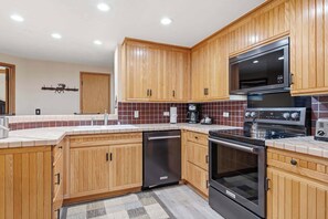 Een moderne keuken met houten kastjes, een ingebouwde oven, een magnetron en een koffiezetapparaat.