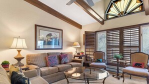 A living room with a sofa, armchairs, a glass coffee table, and a fireplace.