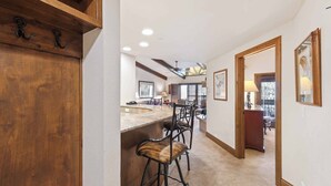 A kitchen with a wooden bar counter, bar stools, and a ceiling fan.