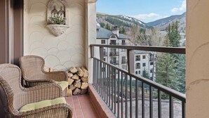 A balcony with wicker chairs, a decorative wall, and a view of a mountainous landscape. - The Charter at Beaver Creek D4805 (Beaver Creek)