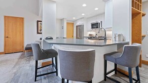 A modern kitchen with a central island, bar stools, and built-in appliances. - The Charter at Beaver Creek D4805 (Beaver Creek)