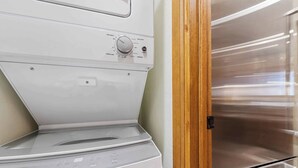 Vue de face d’un lave-linge Whirlpool, avec un sèche-linge en acier inoxydable placé à côté.