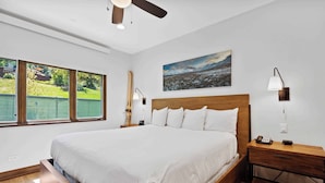 Um quarto com uma cama grande, cabeceira de madeira, mesas de cabeceira e um quadro na parede.
