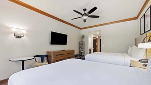 A hotel room with two beds, a ceiling fan, a TV mounted on the wall, and a small table with a chair. - The Charter at Beaver Creek E0405 (Beaver Creek)
