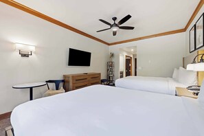 A hotel room with two beds, a ceiling fan, a TV mounted on the wall, and a small table with a chair. - The Charter at Beaver Creek E0405 (Beaver Creek)