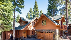 A large log cabin with multiple garage doors, stone foundation, and a stone staircase leading to a deck. - Hot tub! Ski In/Out! Pool Table/PingPong Fireplaces! Mere feet from the Village! (Truckee)