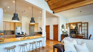 A spacious kitchen with wooden cabinets, a large island with stools, and modern appliances. - Hot tub! Ski In/Out! Pool Table/PingPong Fireplaces! Mere feet from the Village! (Truckee)