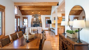 A spacious dining area with a long wooden table, comfortable seating, a stone fireplace, and a large mirror on the wall. - Hot tub! Ski In/Out! Pool Table/PingPong Fireplaces! Mere feet from the Village! (Truckee)