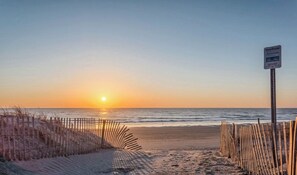 A beach scene with a wooden fence and a signpost.