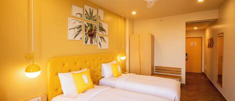 A hotel room with two beds, a ceiling fan, and artwork on the wall.