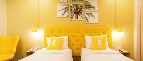 Habitación de hotel con dos camas, paredes amarillas y un ventanal grande.