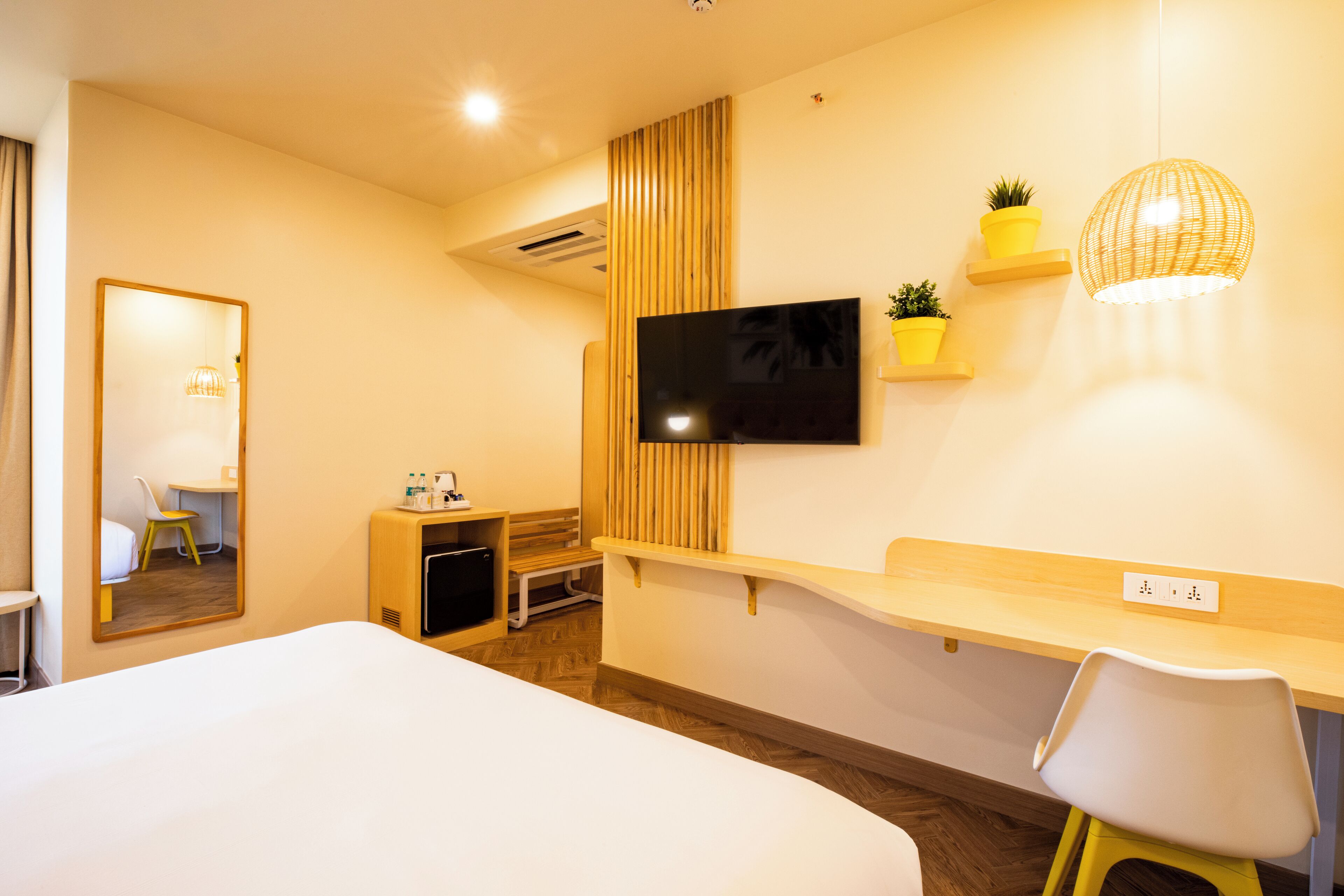A hotel room with a bed, a desk, a TV, and a mirror.