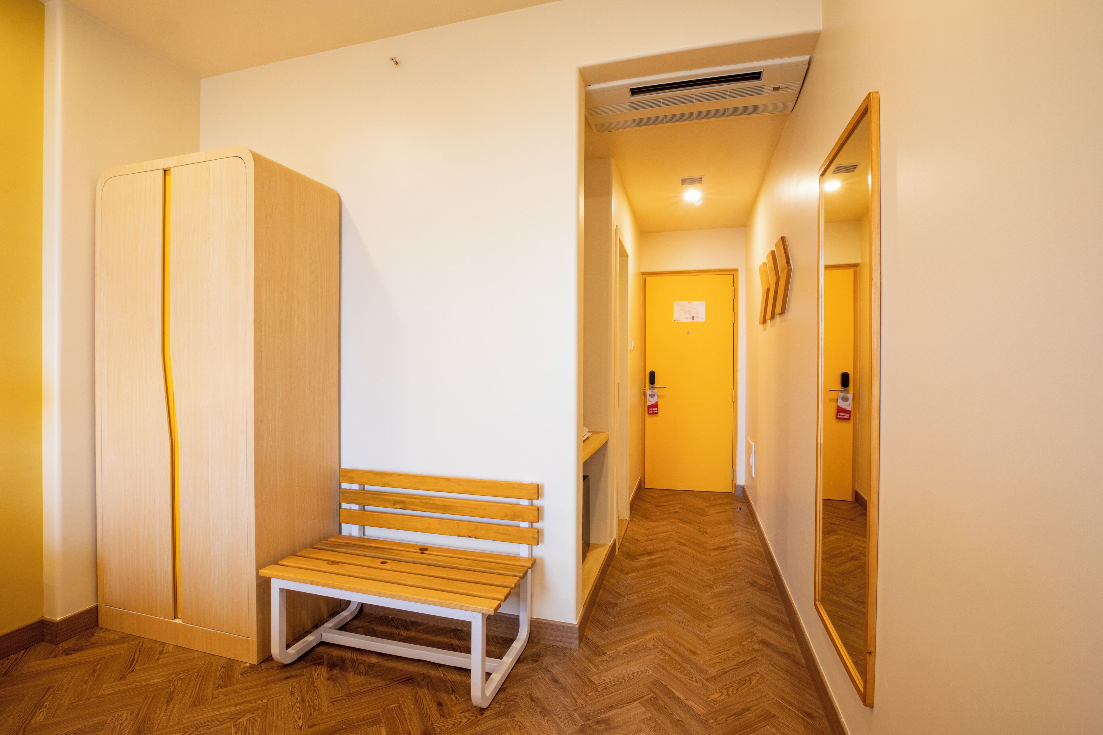 Un pasillo con un banco de madera, un armario y un espejo en la pared.