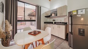 A modern kitchen with a dining area, featuring a refrigerator, microwave, and a dining table with chairs. - Comfortable loft Tranvia 40 center (Medellín)