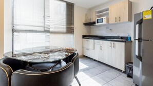A modern kitchen with a dining table, chairs, cabinets, a microwave, and a refrigerator. - Urban Loft: Style and Comfort (Medellín)