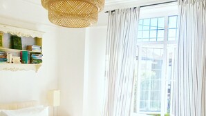 A neatly made bed with white linens, a bedside lamp, and a bookshelf with books. - Zeta Cottage - Ryde, Isle of Wight (Ryde)