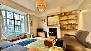 A living room with a fireplace, a sofa, a coffee table, and a television. - Zeta Cottage - Ryde, Isle of Wight (Ryde)