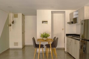 A modern kitchen with a dining area, featuring a stainless steel refrigerator, a stove, and a potted plant on the table. - Queen bed and street view! (Medellín)