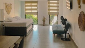 Une pièce moderne et bien éclairée, comprenant un lit, une table à manger et un coin salon.