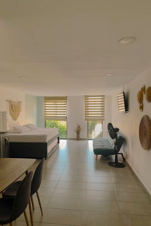 A modern, well-lit room with a bed, a dining table, and a seating area.