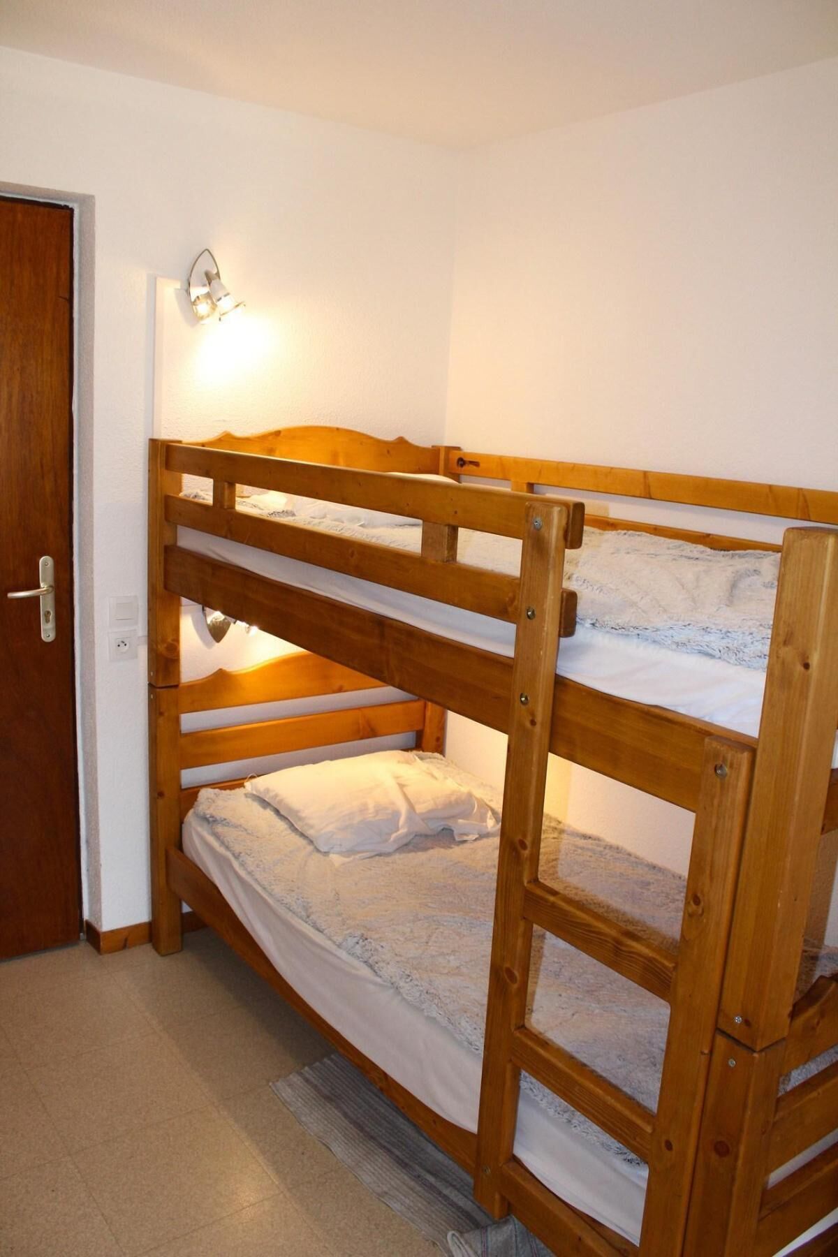 A bunk bed with a headboard and a wall-mounted light fixture.