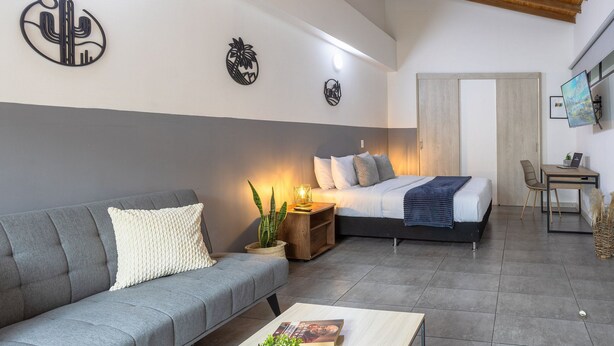 A modern bedroom with a bed, a sofa, a desk, and a small table. - Central location, close to Tranvia (Medellín)