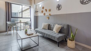 A modern living room with a grey sofa, a coffee table, and a dining area with chairs and a table. - Central location, close to Tranvia (Medellín)