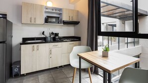 A modern kitchen with light wood cabinets, a black countertop, and a stainless steel refrigerator. - Central location, close to Tranvia (Medellín)