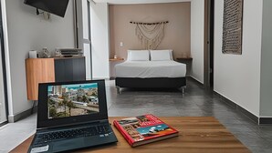 A modern hotel room with a bed, a laptop on a wooden table, and a magazine. - Large spaces, unique location (Medellín)