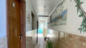 Un pasillo con puerta de madera, paredes con azulejos y una planta en maceta.