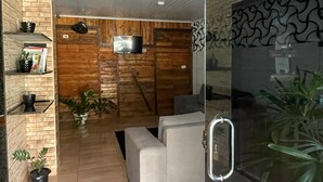 Una sala de estar moderna con una pared de madera, un sofá, un televisor y una partición de vidrio.