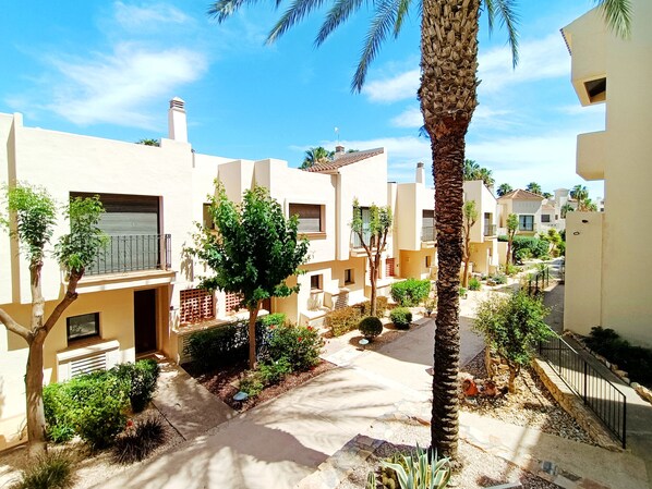 A residential area with modern buildings, a central pathway, and surrounding greenery.