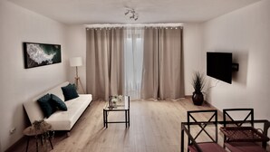 A modern living room with a white sofa, a glass coffee table, and a TV mounted on the wall. - Moderno Apartamento en Puerto de Lacruz (Puerto de la Cruz)