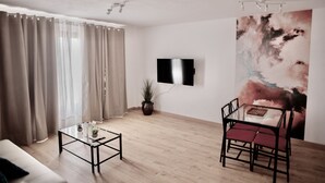 A modern living room with a sofa, coffee table, TV, and a painting on the wall. - Moderno Apartamento en Puerto de Lacruz (Puerto de la Cruz)