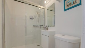 Ein modernes Badezimmer mit einer Duschkabine, einem weißen Waschbecken und einer Toilette.